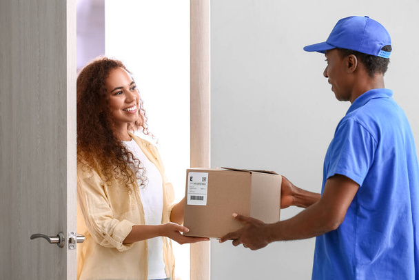 Mujer afroamericana recibiendo paquete de la empresa de mensajería de la entrega - Foto, Imagen