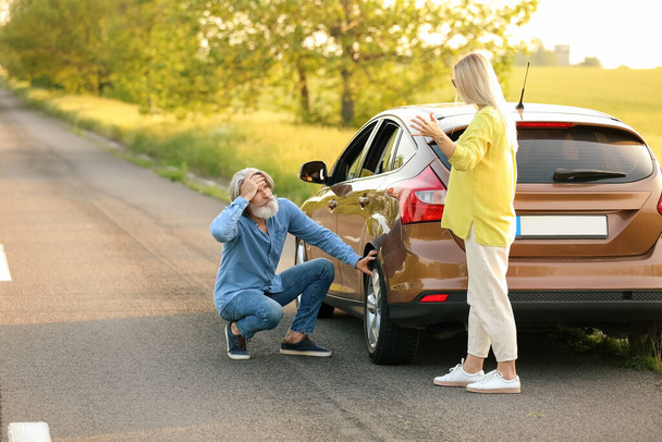 Couple d'âge mûr stressé près de voiture endommagée à l'extérieur - Photo, image