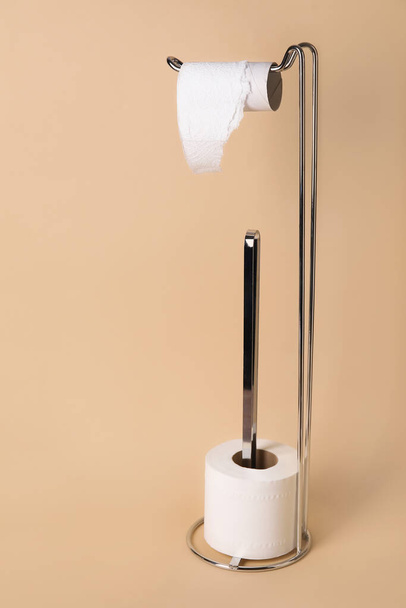 Holder with cardboard tube and toilet paper roll on beige background - Photo, Image