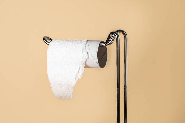 Holder with cardboard tube for toilet paper on beige background, closeup - Fotó, kép