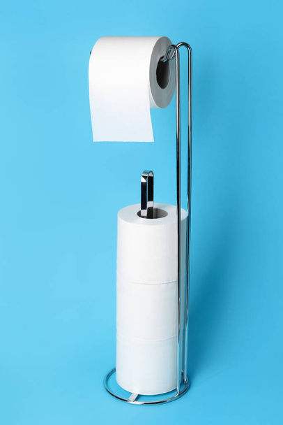 Σύγχρονη κάτοχος με ρολό χαρτί τουαλέτας σε μπλε φόντο - Φωτογραφία, εικόνα