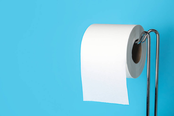 Soporte moderno con rollo de papel higiénico sobre fondo azul, primer plano - Foto, imagen