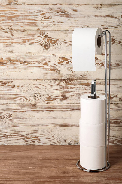 Holder with toilet paper rolls on wooden background - 写真・画像