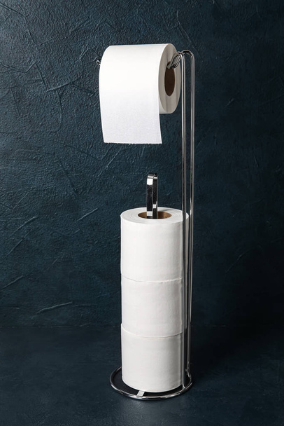 Holder with toilet paper rolls on dark background - Foto, imagen