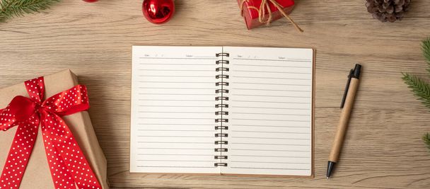 Блокнот, рождественский подарок и ручка на деревянном столе, вид сверху и копировальное пространство. Xmas, Happy New Year, Goals, Resolution, To do list, Faby and Plan concept - Фото, изображение
