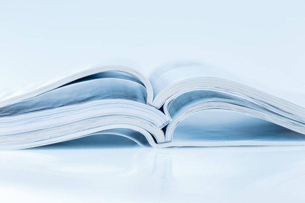 Stapel open magazines in blauwe toon op witte achtergrond met kopieerruimte - Foto, afbeelding