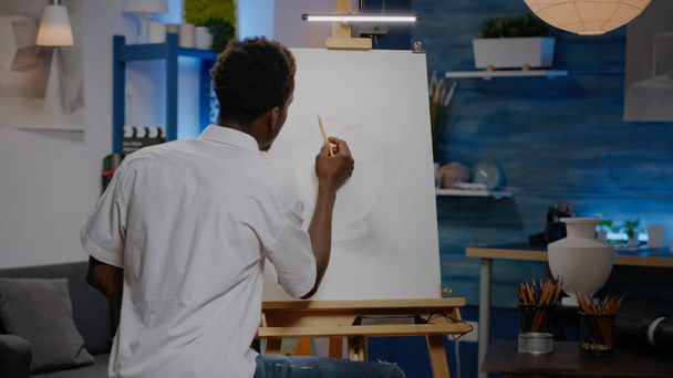 Африканська доросла людина, яка користується олівцем на полотняному малюнку. - Фото, зображення