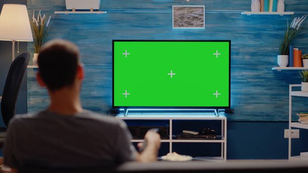 Man using TV remote on green screen background - Photo, Image