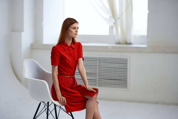 Kaunis nainen punaisessa mekossa istuu ikkunan lähellä muoti - Valokuva, kuva