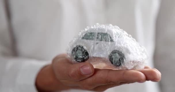 Γυναίκα χέρι κρατώντας το αυτοκίνητο παιχνίδι σε προστατευτική πλαστική μεμβράνη 4k ταινία - Πλάνα, βίντεο