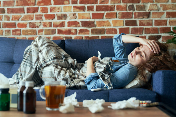 Malade femme caucasienne couché sur le canapé et ayant un mal de tête  - Photo, image