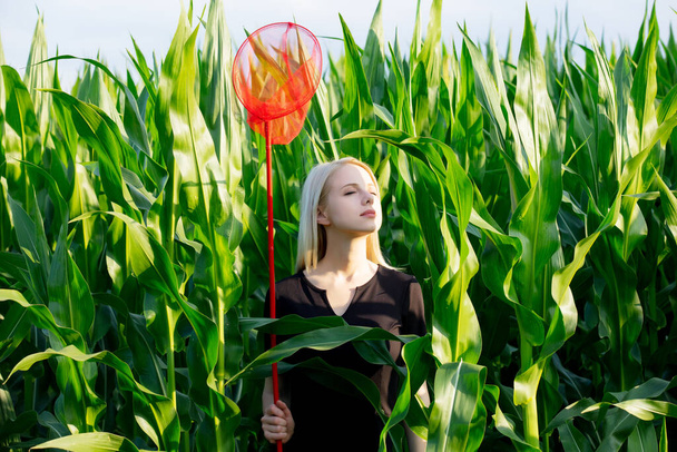 Blondýny žena v černých šatech s motýlí sítí v kukuřičném poli  - Fotografie, Obrázek