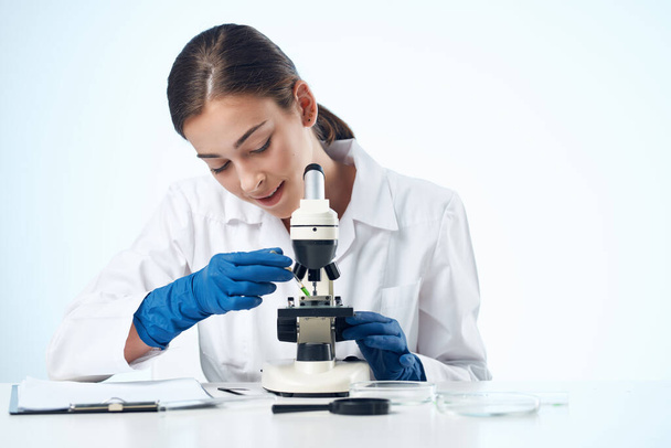 kobieta lekarz siedzi przy stole mikroskop badania Studio - Zdjęcie, obraz