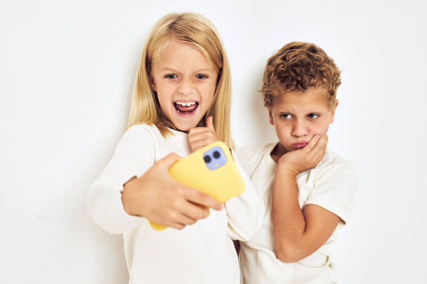 Dwa dzieci w wieku przedszkolnym chłopiec i dziewczyna z żółty telefon rozrywki styl życia dzieciństwo - Zdjęcie, obraz