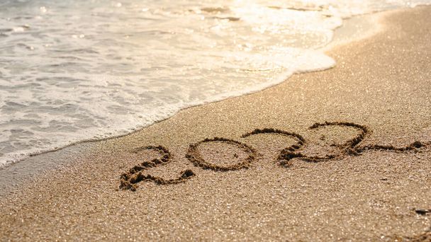 The concept of waiting for the new year and new life. The inscription Evening 2022 against the backdrop of bright sunlight and sea waves. - Zdjęcie, obraz