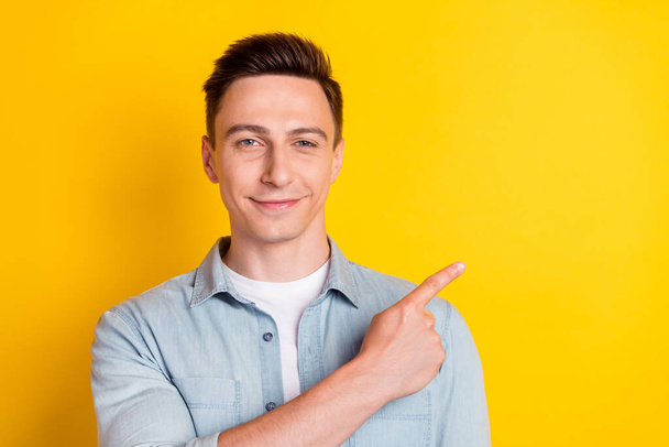 Portrait of young attractive smiling good mood man point finger copyspace recommend isolated on yellow color background - Valokuva, kuva