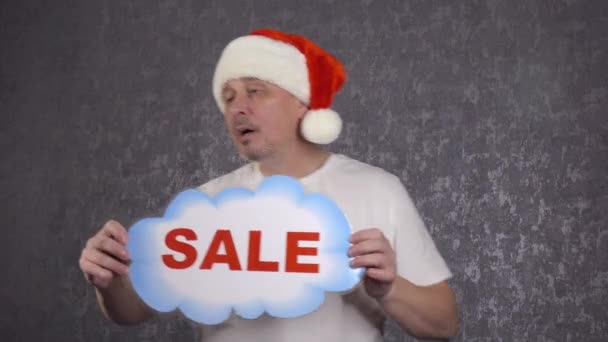 Mężczyzna w kapeluszu Świętego Mikołaja oferuje sprzedaż.. - Materiał filmowy, wideo