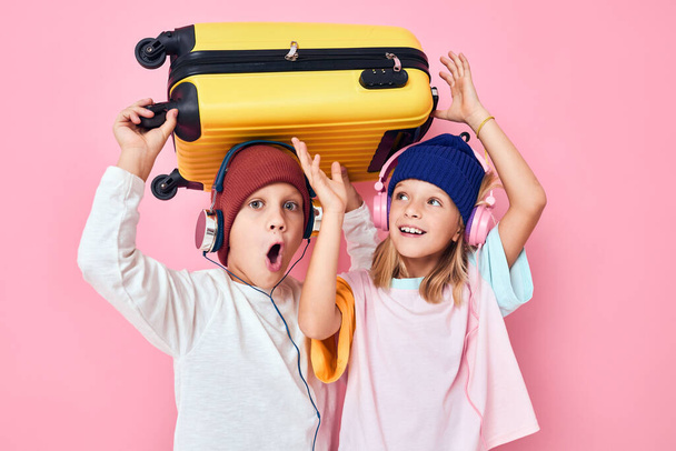 funny little boy and girl yellow suitcase with headphones studio posing - Photo, Image