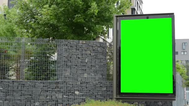 Billboard in de stad - groene scherm - stenen omheining met bomen - gebouw - Video