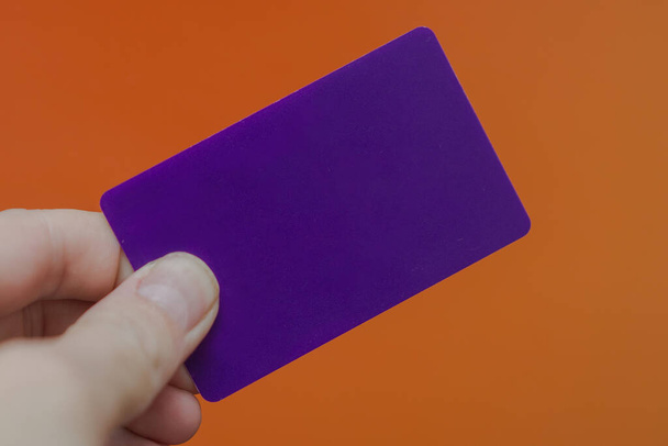 carte plastique vierge violet à la main sur fond orange - Photo, image