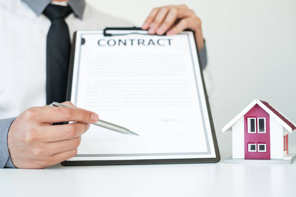Agenten, die in Immobilieninvestitionen tätig sind, halten den Schlüssel für die Hausratversicherung in der Hand und unterzeichnen Verträge in Übereinstimmung mit den Verträgen über den Hauskauf, die Käufe für Kunden genehmigen.. - Foto, Bild