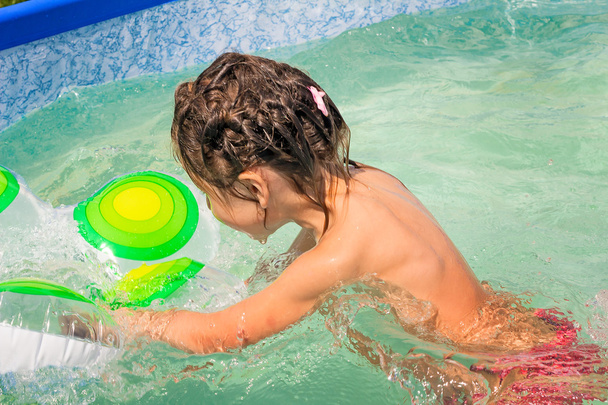 A menina brinca na piscina com um anel de borracha
. - Foto, Imagem