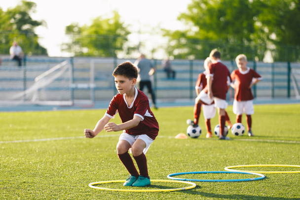 Young Boys beim Sportunterricht im Freien. Kinder springen hoch in Hula-Hoop-Reifen. Fußballteam auf Trainingseinheit.  - Foto, Bild