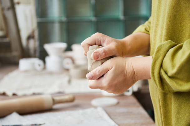 Vrouwelijke keramist werkzaam in aardewerk studio. Keramist 's handen vuil van klei. Proces van het maken van aardewerk. Master keramiste werkt in haar atelier - Foto, afbeelding