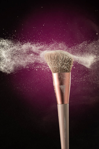 cosmetic brush with stream splash dusty plume of cosmetics on black background - Foto, afbeelding