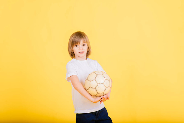 Porträt eines Jungen mit Fußballball, gelber Hintergrund im Studio - Foto, Bild