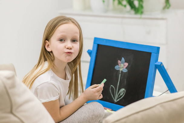 Photo of blonde girl drawing a flower on the white board. - Φωτογραφία, εικόνα