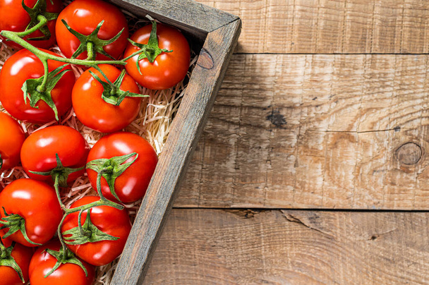 Reife rote Tomaten in hölzerner Marktbox. Holzuntergrund. Ansicht von oben. Kopierraum - Foto, Bild