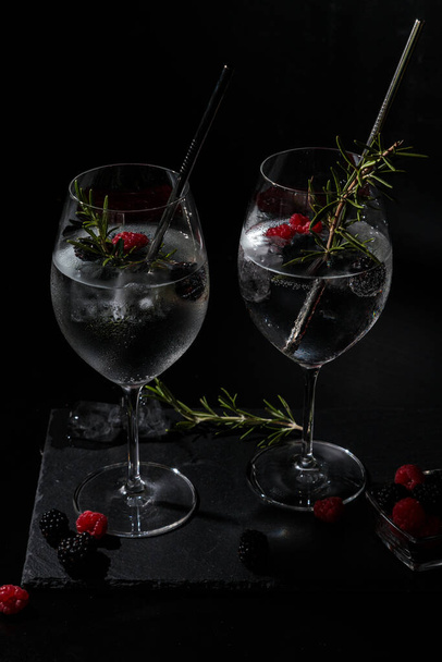 two summer gin tonc with berry and rosemary on a black background - Foto, immagini