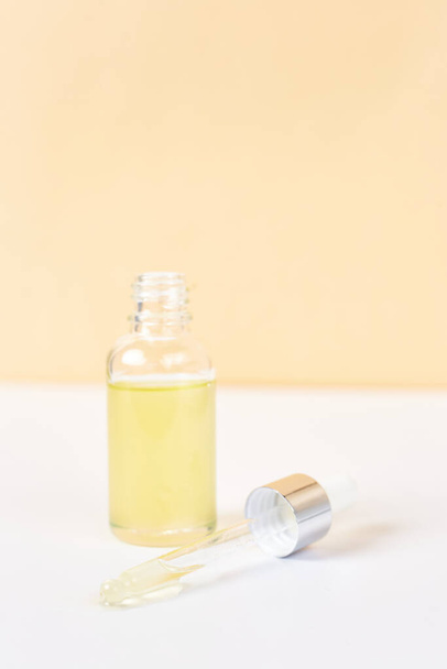 Pipette with essential oil over bottle on white and yellow background. Natural medicine concept. Aromatherapy  - Foto, imagen