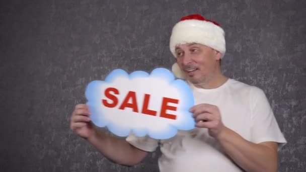 A man in a Santa Claus hat offers a sale. - Footage, Video