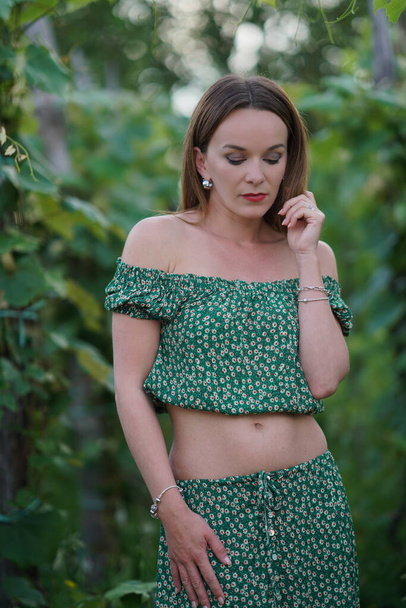 A young beautiful caucasian female in a two-piece matching outfit posing outdoors - 写真・画像