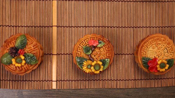 Colorful flower decorated mooncake Chinese mid autumn festival on bamboo food mat background - Photo, Image