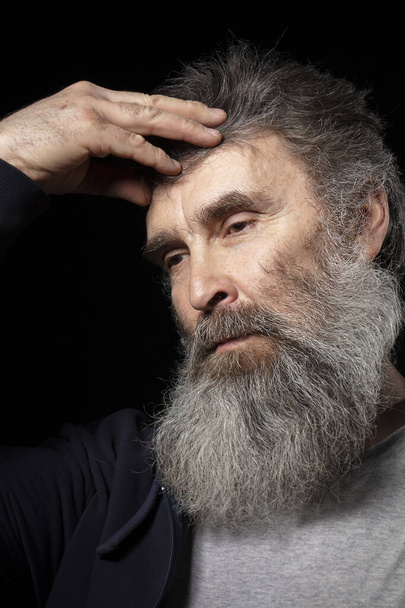 Портрет пожилого человека с седой бородой на черном фоне. - Фото, изображение