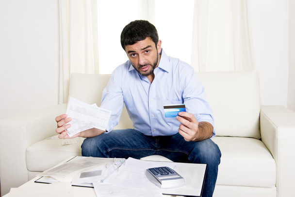 Latin business man worried paying bills on couch - Foto, Imagen