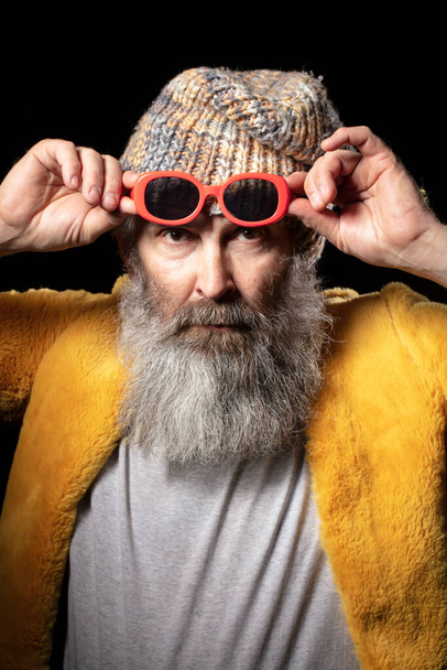 Függőleges portré egy idős férfiról, divatos ruhákban és piros szemüvegben.. - Fotó, kép