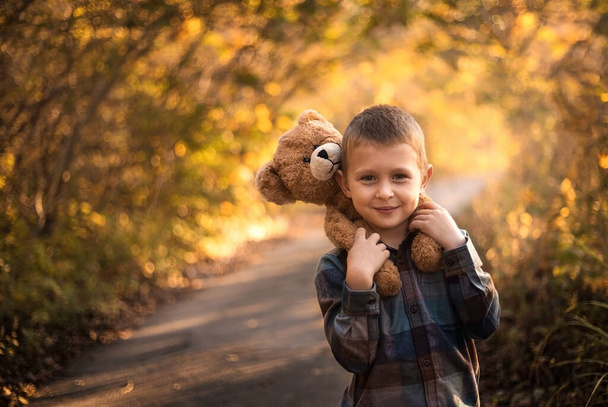 preschool boy stands and holds a teddy bear toy on his shoulders - Foto, Imagem