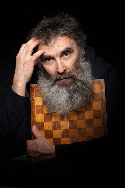 Портрет літнього чоловіка з сірою бородою з шахівницею
. - Фото, зображення