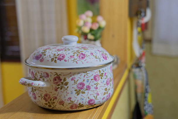 closeup of a white saucepan decorated with pink flowers and unfocused background - Foto, Imagem