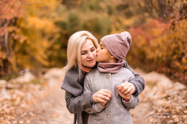 boldog család anya és gyermek lánya játszani és nevetni az őszi séta. Anya és gyermek kapcsolatok. Divatos anya és lánya, ugyanolyan kabátban, elegáns külsővel. - Fotó, kép