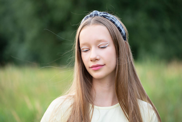 Portré egy tizenéves lány kreatív smink és hosszú szőke haj a természet háttér. - Fotó, kép
