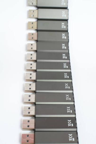 Vertical close up de varas USB pretas que colocam em uma fileira com fundo branco. macro tiro foco seletivo de drives flash modernos com conexões de metal. - Foto, Imagem