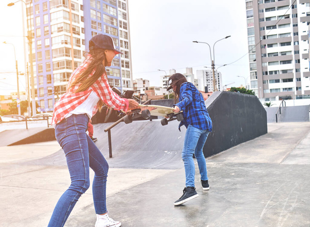 Boze meisjes vechten voor een skateboard in het skate park. vrienden die worstelen parodie. - Foto, afbeelding