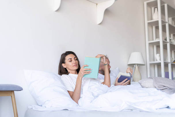 Молода пара чоловік з дружиною вдома в ліжку читає книги в осінній зимовий вечір
 - Фото, зображення