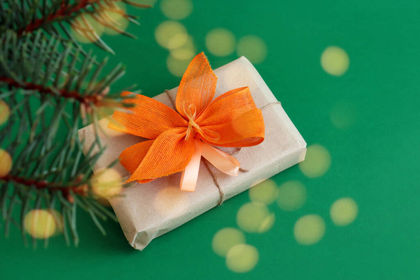 The concept of preparing New Year's gifts. Packaged gift with a yellow bow on a green background, close-up, bokeh - Foto, immagini
