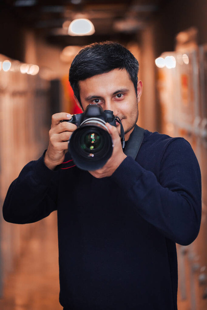Фотограф держит камеру в руке и фотографирует с большим объективом. Фотосъемка - Фото, изображение